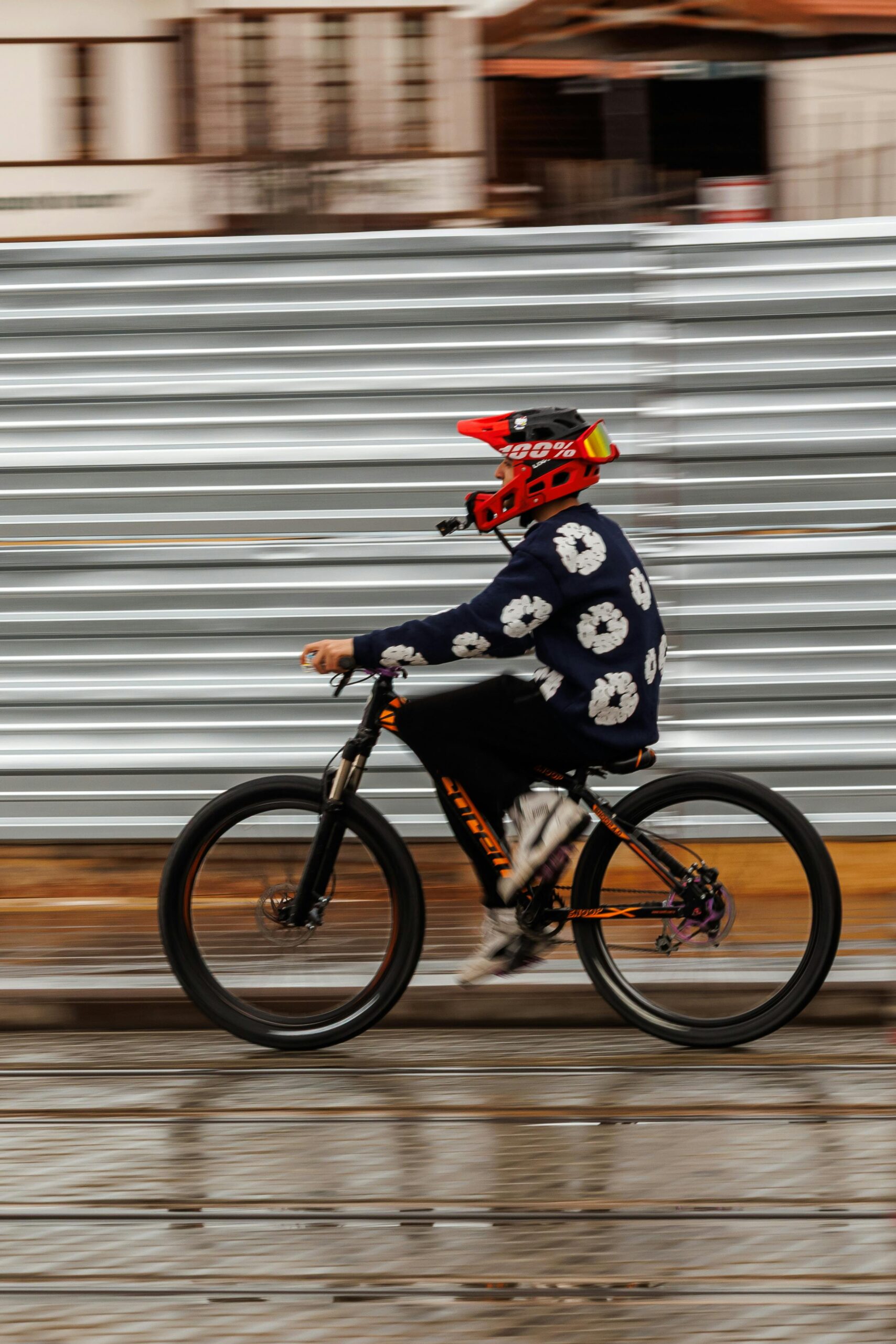 A person wearing a red helmet cycles swiftly on a city street, showcasing motion and speed.